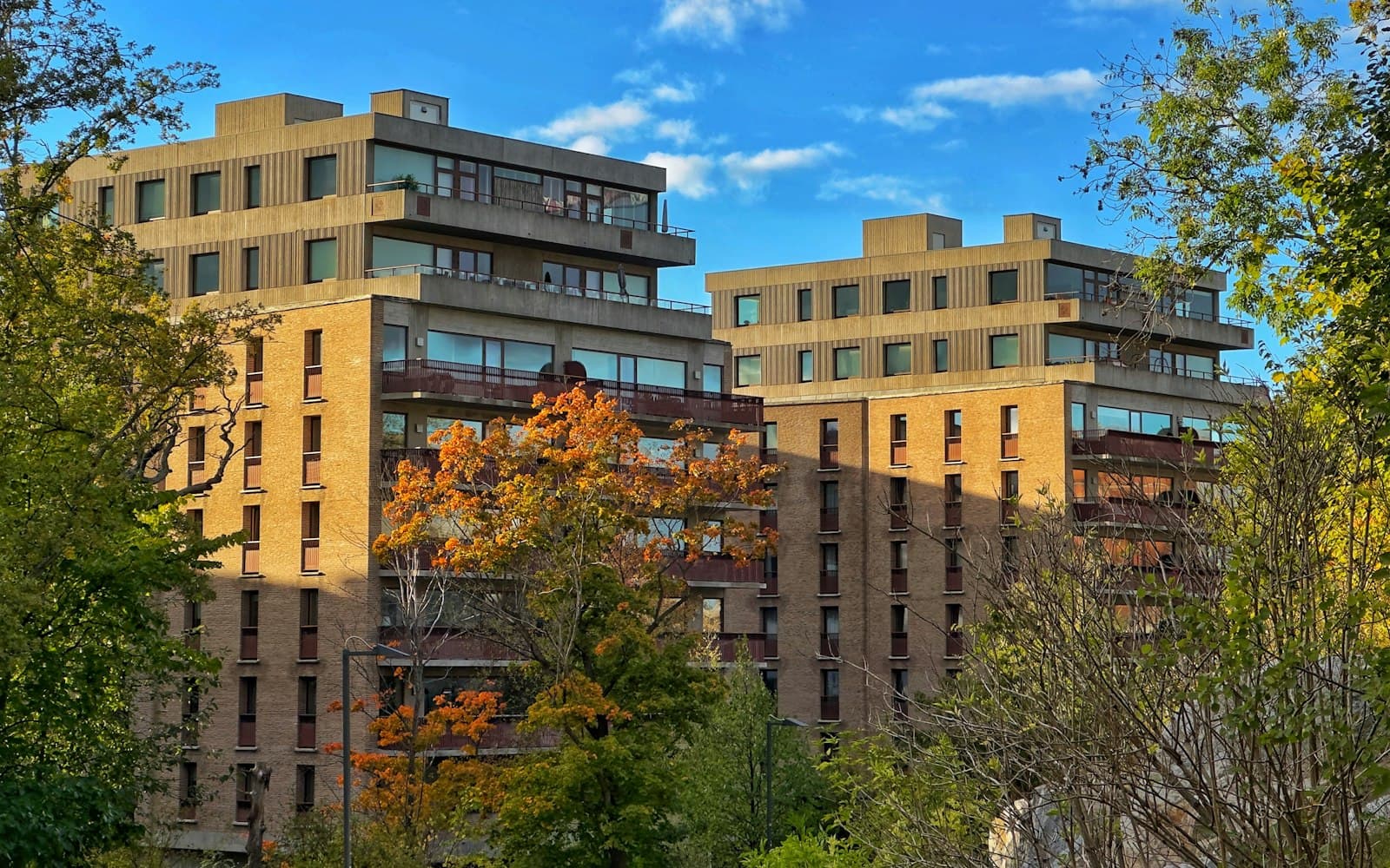 Två tegelbyggnader med träd i förgrunden — typisk svensk bostadsmiljö