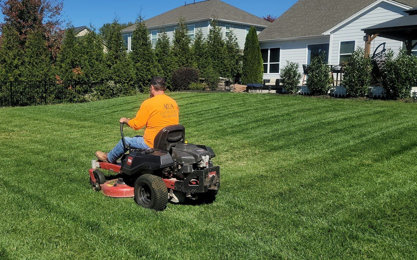 Sittgräsklippare på en gräsmatta intill bostadshus