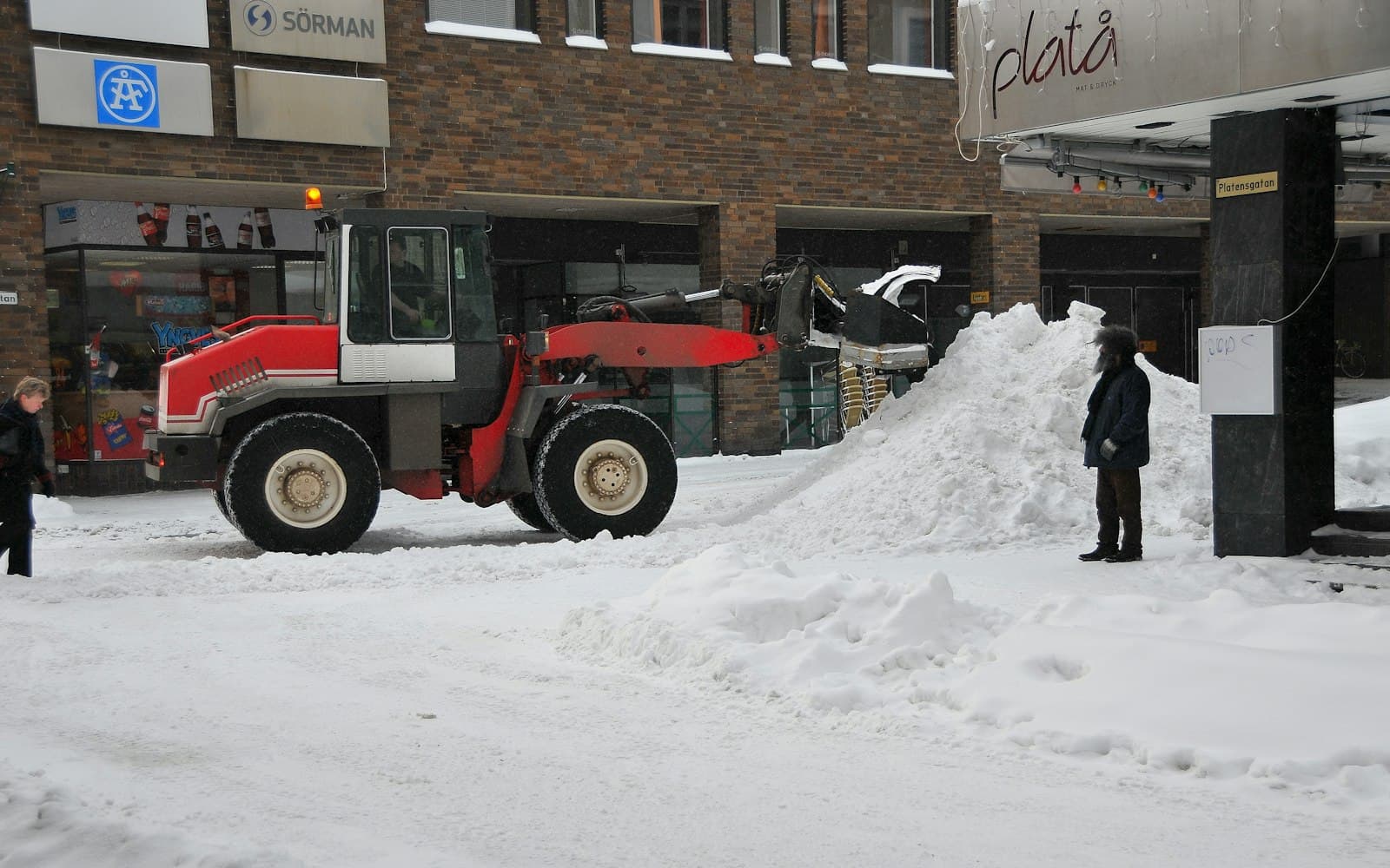 Snöröjningsmaskin som plogar bort snö i bostadsområde